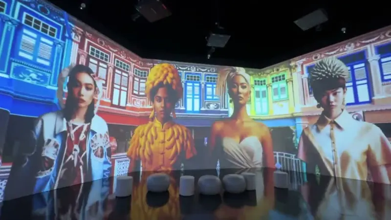 SingaPop! 2025 immersive AI art installation: a wrap-around projection room of AI-generated portraits in fruit- and flower-inspired costumes, set against Peranakan shophouses and HDB blocks